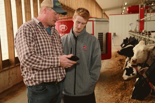 Todd Holmdale and son in dairy barn looking at Lely app