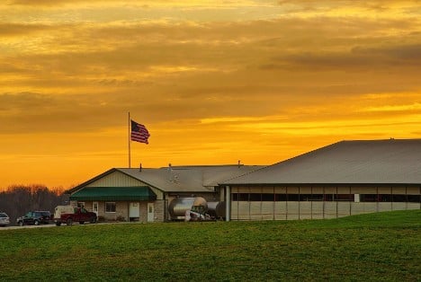 Dairy barn refitted for milking robots pictured at sunset.